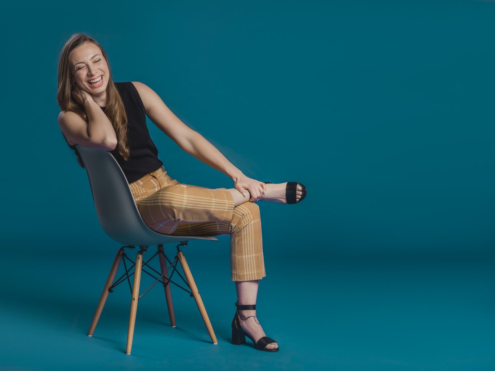 Dr. Jessica Metcalfe laughing, seated on a chair against a teal backdrop